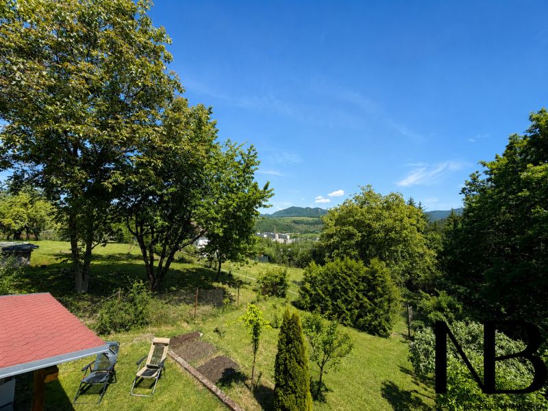 Der Garten der Hütte auf Klučina in Považská Bystrica mit üppigem Grün und Stühlen.