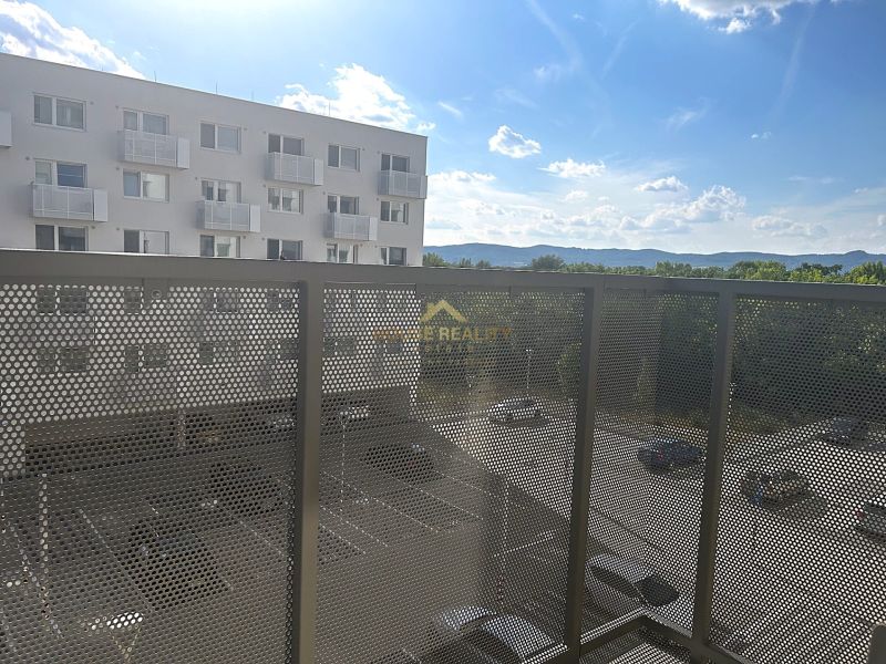 Balkon in einer Einzimmerwohnung mit Blick auf den Parkplatz und die umliegenden Berge.