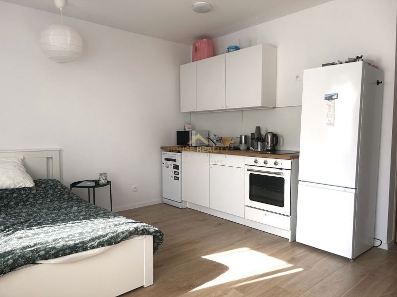 Kompakte Küche mit eingebauten Geräten und Holzboden in einer Einzimmerwohnung.