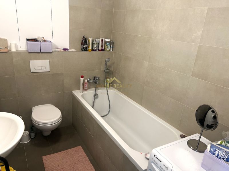 Badezimmer mit Badewanne, Toilette und Waschmaschine in einer Einzimmerwohnung.