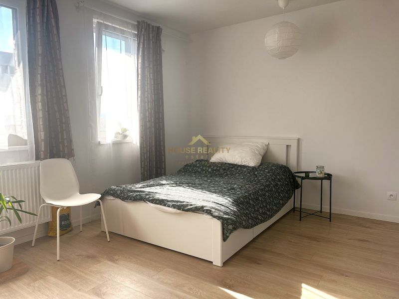 Helles Zimmer in einer Einzimmerwohnung mit Bett und Holzboden.