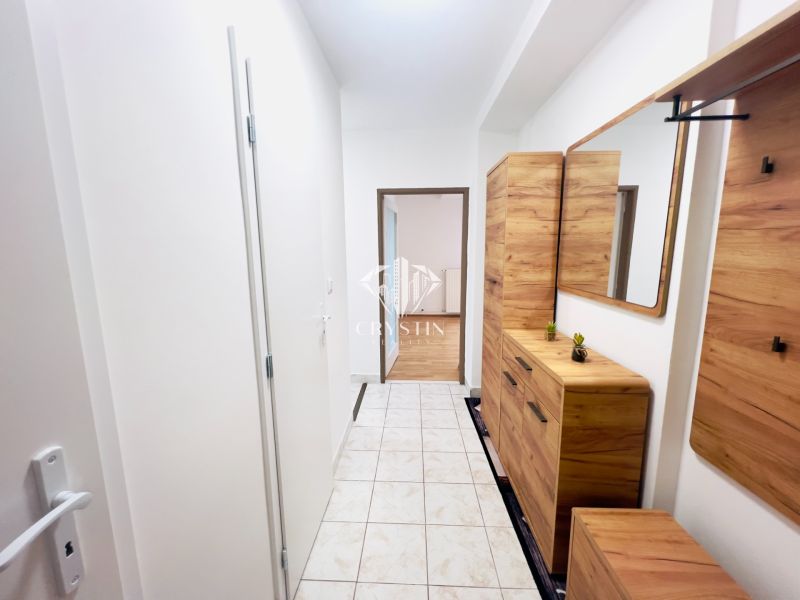 Der Flur in einer 2-Zimmer-Wohnung mit Fliesen und Holzmöbeldekor.