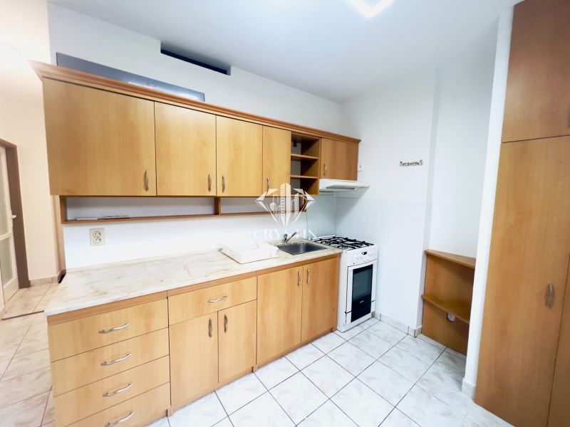 Küche in einer 2-Zimmer-Wohnung mit Keramikfliesen und Holzschränken.