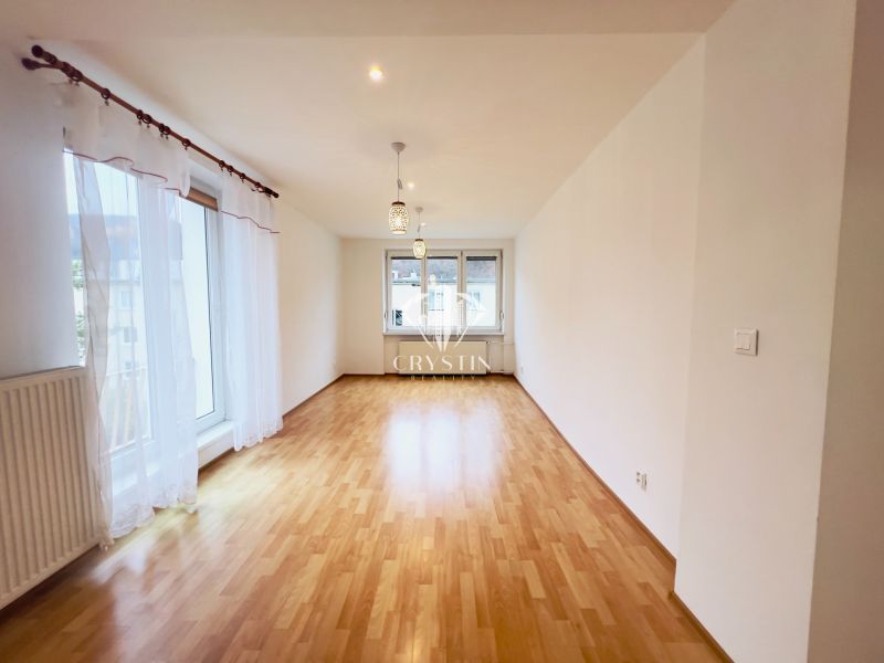 Helles Wohnzimmer in einer 2-Zimmer-Wohnung mit Holzboden und großen Fenstern.