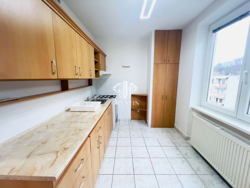 Küche mit Holzdekor und weißen Fliesen in einer 2-Zimmer-Wohnung.