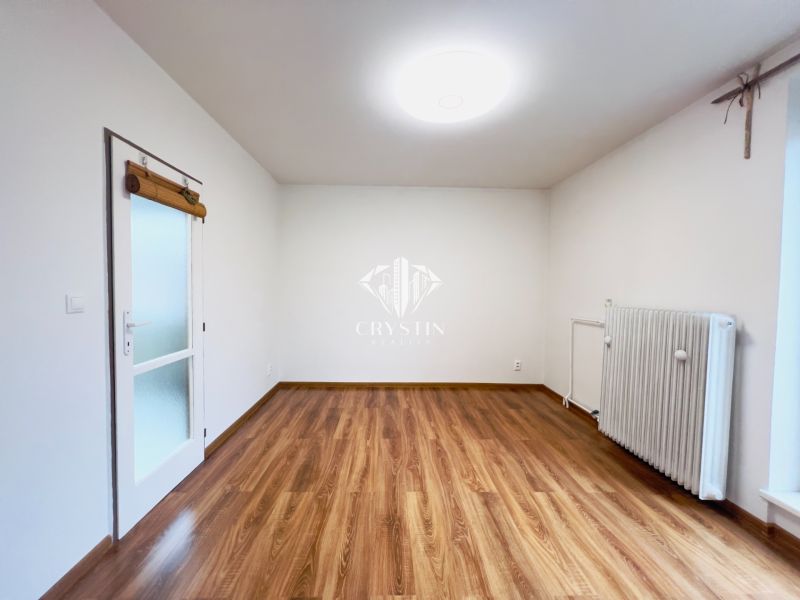 Ein Zimmer in einer 2-Zimmer-Wohnung mit einem Boden in Holzoptik und einem Heizkörper.