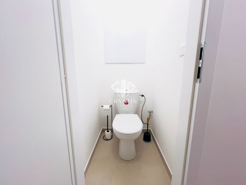 Toilette mit weißen Wänden in einer 2-Zimmer-Wohnung, einfache sanitäre Ausstattung.