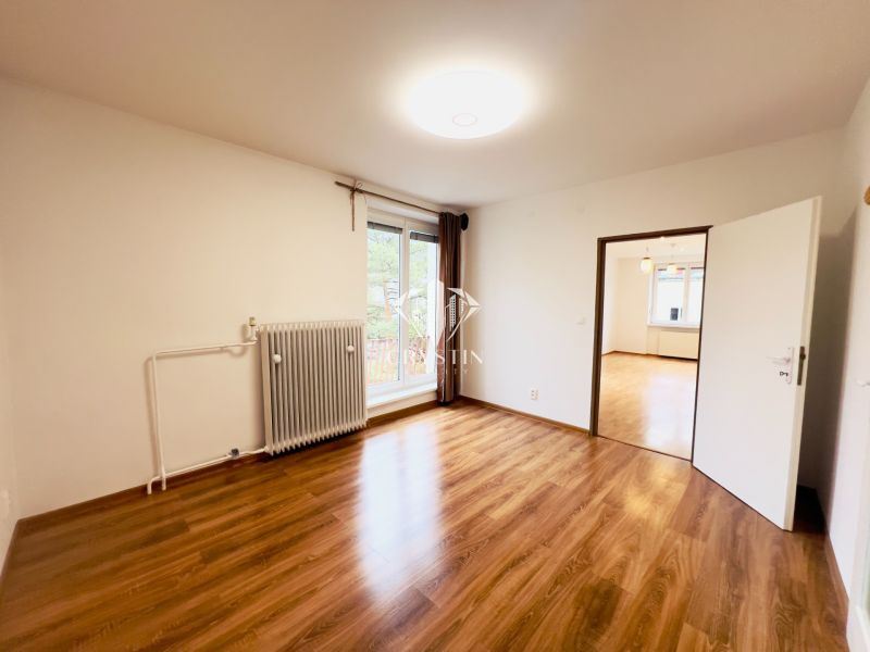 Ein Zimmer in einer 2-Zimmer-Wohnung mit großen Fenstern und einem Boden in Holzoptik.