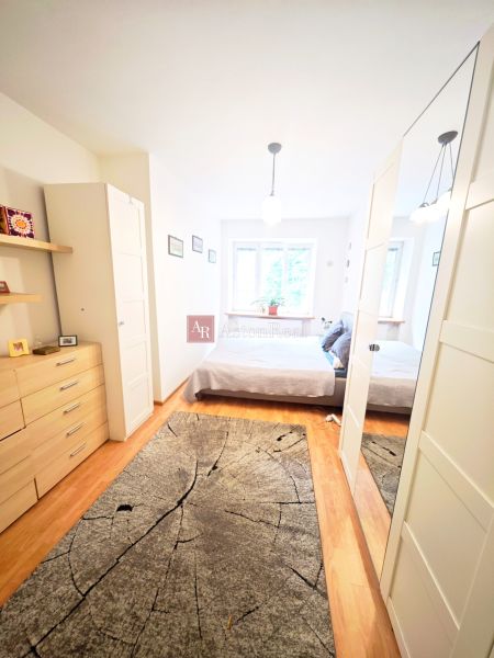 Helles Schlafzimmer in einer 2-Zimmer-Wohnung mit Holzboden und Spiegelschrank.