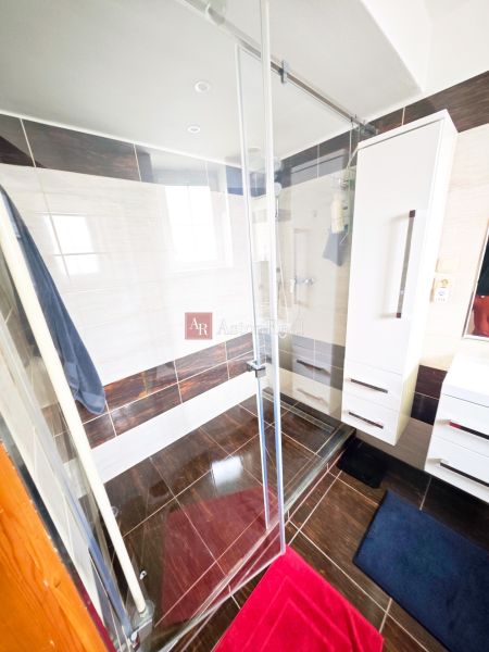 Badezimmer in einer 2-Zimmer-Wohnung mit Duschkabine und Boden in Holzoptik.