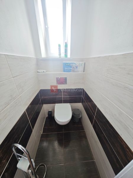 Badezimmer mit Toilette in einer 2-Zimmer-Wohnung, Fliesen mit Holzdekor an den Wänden.