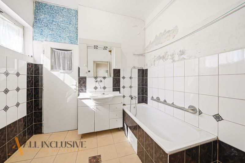 Badezimmer in einem Einfamilienhaus mit weißer Badewanne und Mosaikfliesen.