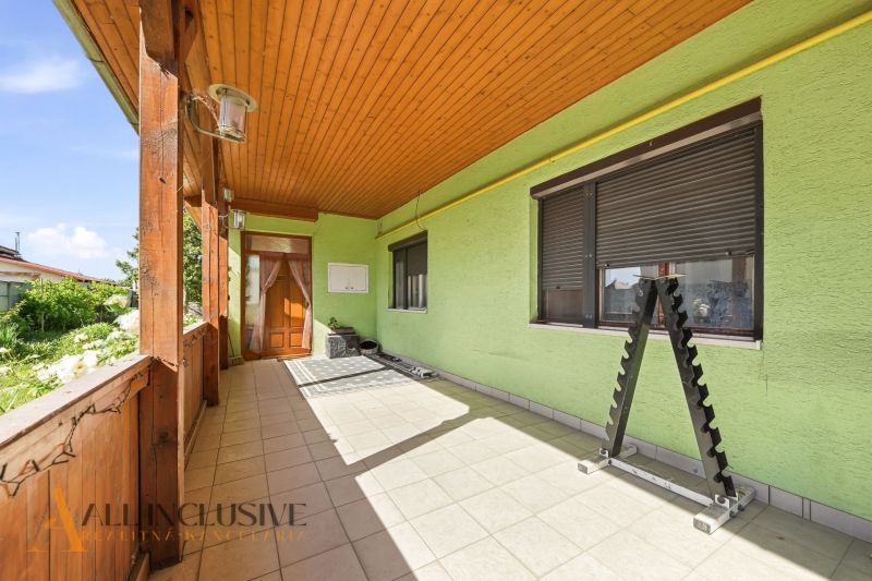 Ein Einfamilienhaus in Hviezdoslavov mit dekorierter Terrasse und Pflastersteinen, hellgrüner Putz.