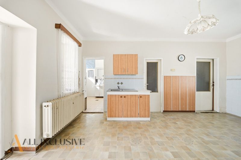 Eine Küche in einem Einfamilienhaus mit einem Boden in Holzoptik und Holzschränken.