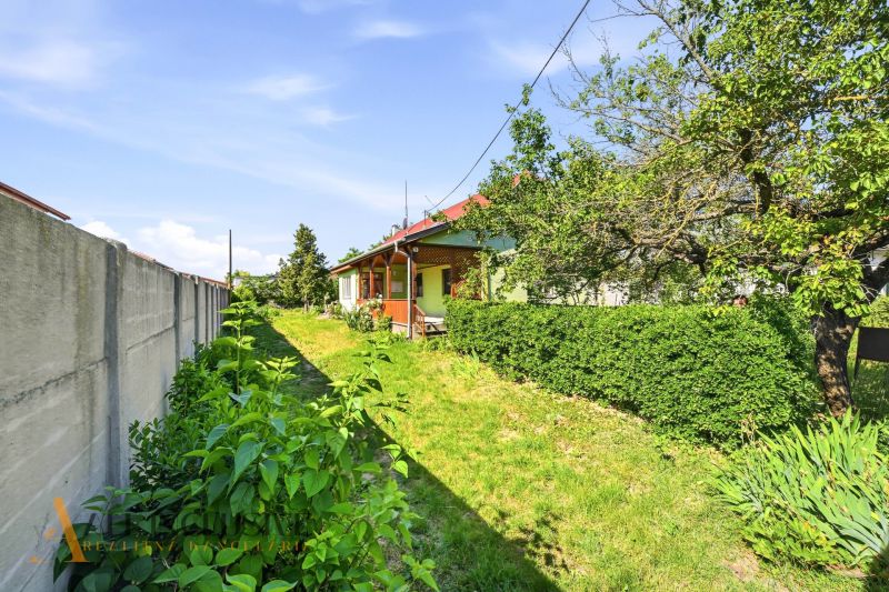 Ein Einfamilienhaus in Hviezdoslavov mit Garten, grünen Sträuchern und einer Rasenfläche neben einem Betonzaun.