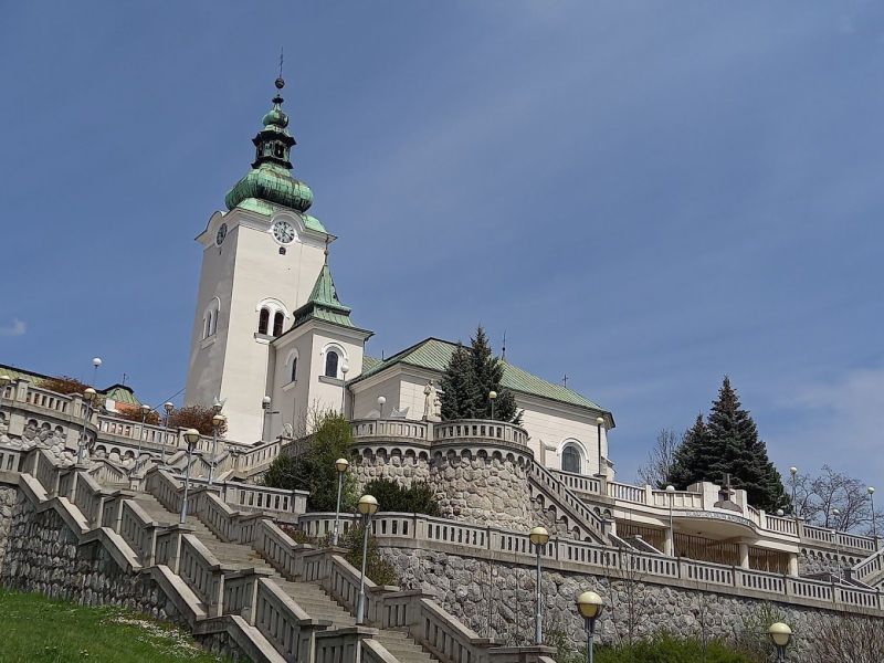 Eine Kirche mit einem Turm, umgeben von einer Treppe und Grünflächen in Ružomberok.