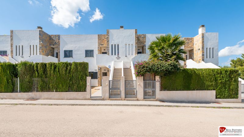 Ferienwohnung in Cala Murada auf Mallorca mit moderner Fassade und grünem Zaun.