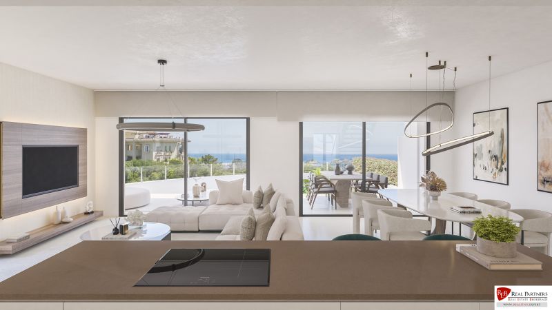Wohnzimmer einer Ferienwohnung mit Blick auf die Terrasse und das Meer, helle Farben.