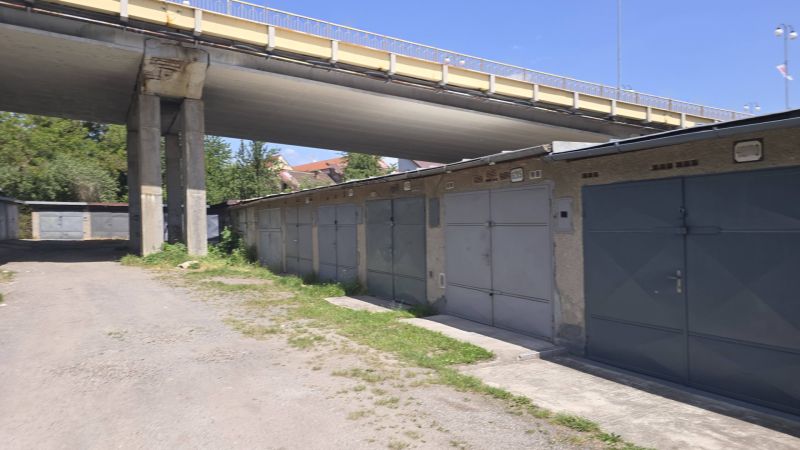 Garagen in der Jesenského-Straße in Zvolen unter der Brücke, umgeben von Grünflächen und einem Schotterweg.