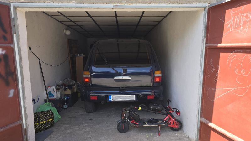 Garage mit Auto und Elektroroller, gelagerten Gegenständen und Zeichnung an der Tür.