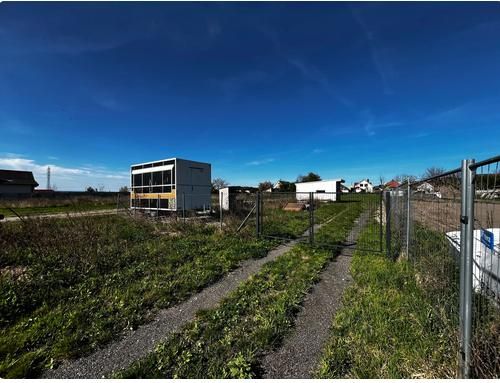 Grundstücke - Wohnen in Pernek mit Containern, Zäunen und einem grasbewachsenen Weg auf dem Land.