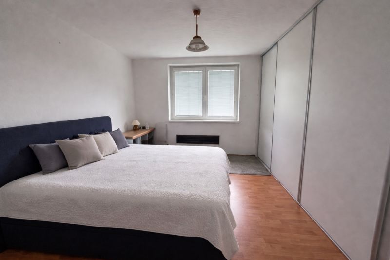 Schlafzimmer mit großem Bett und Holzboden in einem Einfamilienhaus.