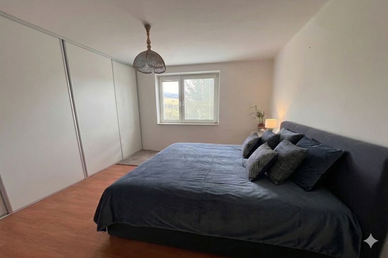 Schlafzimmer in einem Einfamilienhaus mit Bett, Holzboden und Einbauschrank.