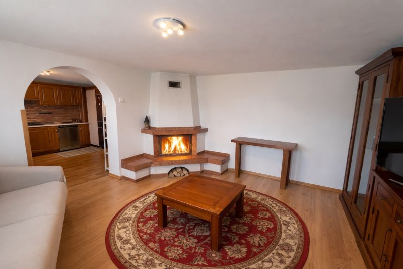 Wohnzimmer in einem Einfamilienhaus mit Kamin, Holzboden und einem bogenförmigen Durchgang.