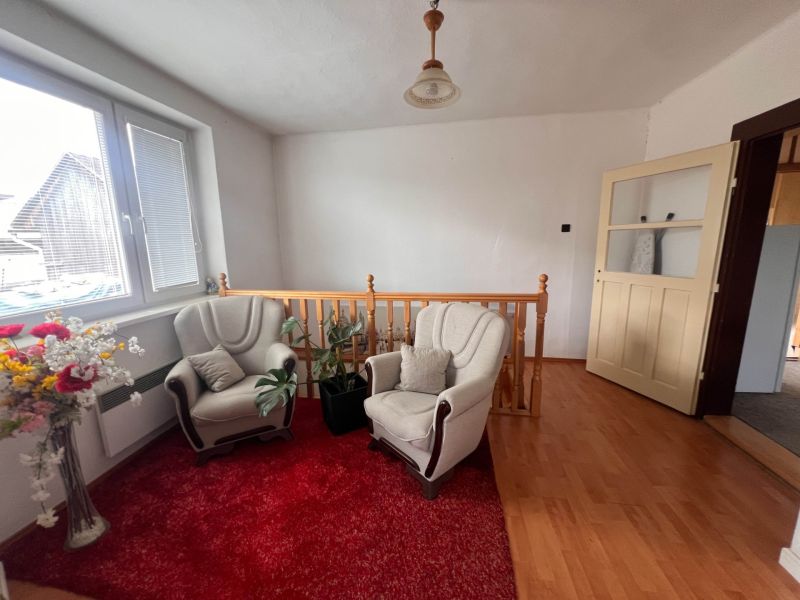 Innenraum eines Einfamilienhauses mit Sofas, rotem Teppich und Holzboden.