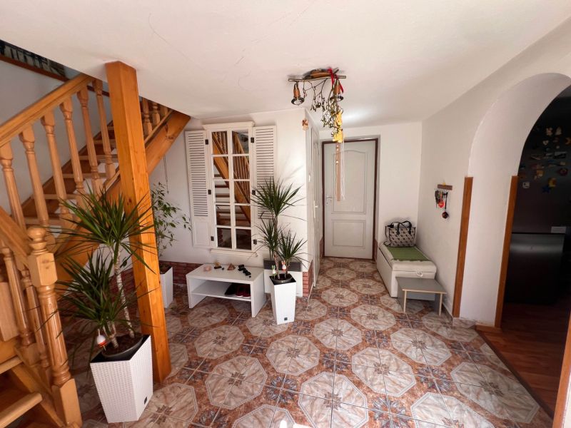 Innenraum eines Einfamilienhauses mit Treppe, Pflanzen und Fliesen in warmen Farbtönen.
