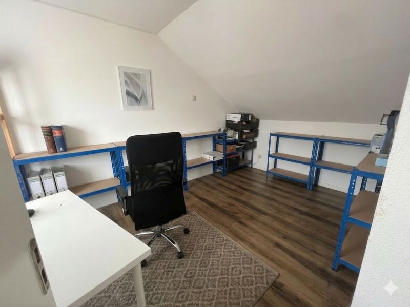 Büro in einem Einfamilienhaus mit Holzboden, Regalsystem und Schreibtisch.