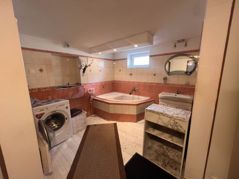 Badezimmer in einem Einfamilienhaus mit Badewanne, Waschmaschine, Waschbecken und Boden mit Holzdekor.