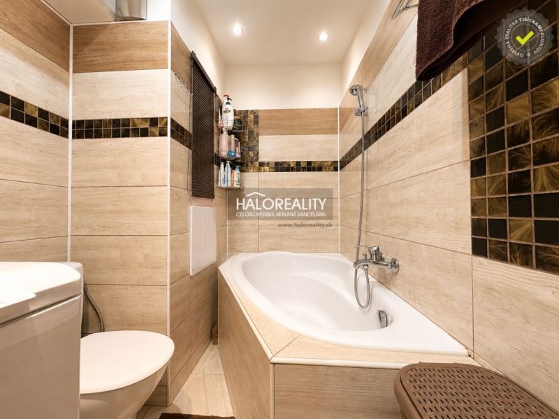 Badezimmer mit Badewanne, moderner Fliese und WC in einer Einzimmerwohnung.