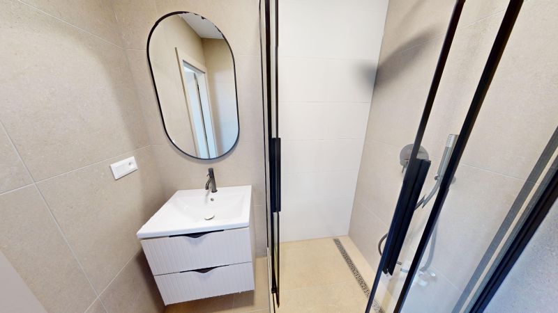 Badezimmer mit Waschbecken und Spiegel in einer 2-Zimmer-Wohnung.