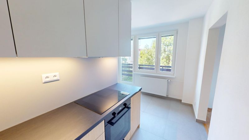 Küche in einer 2-Zimmer-Wohnung mit Glaskeramik-Kochfeld und großem Fenster.