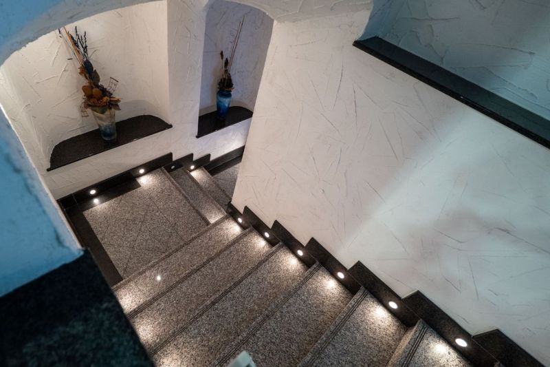 Eine Treppe mit Beleuchtung, verziert mit Vasen, texturierte Wände in einer besonderen Immobilie.