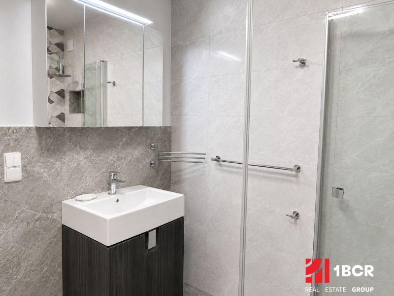 Badezimmer mit Waschbecken, Spiegel und Duschkabine in einer 3-Zimmer-Wohnung.