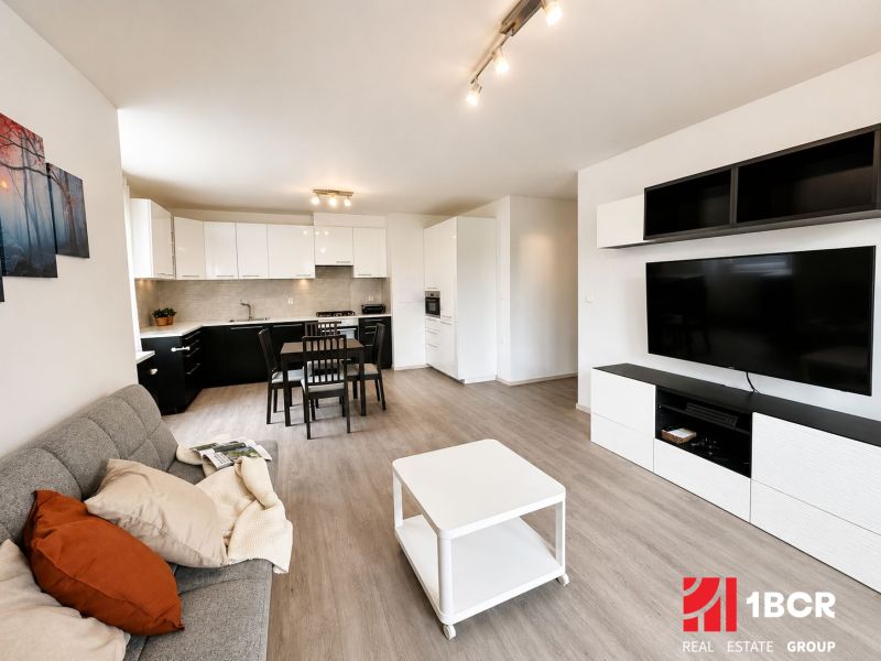 Wohnzimmer in einer 3-Zimmer-Wohnung mit Holzboden und Eckküche.