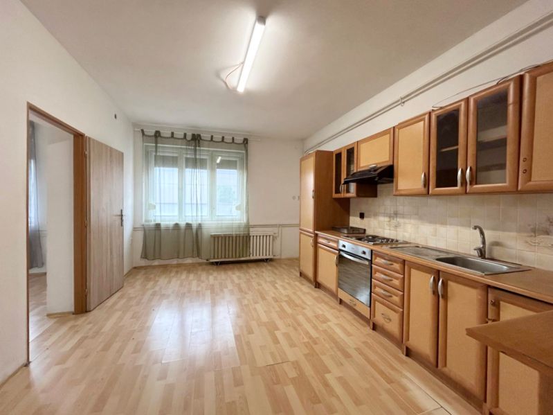 Küche in einem Einfamilienhaus mit heller Küchenzeile und Boden in Holzoptik.