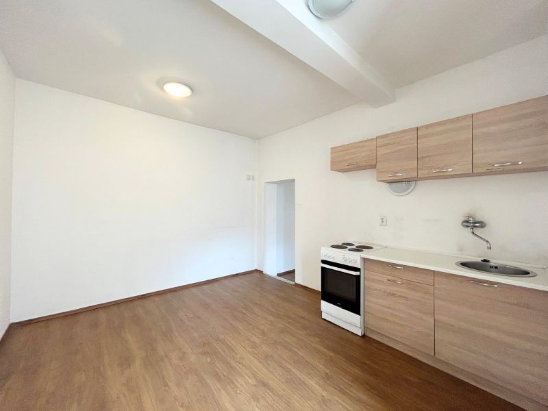 Küche in einem Einfamilienhaus mit einfacher Küchenzeile und Boden in Holzoptik.