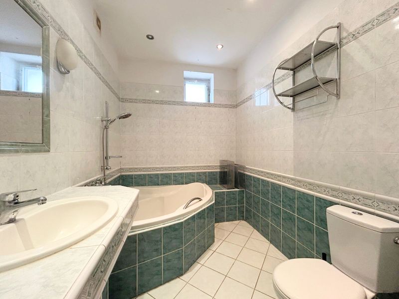 Badezimmer in einem Einfamilienhaus mit Badewanne, Waschbecken, Spiegel und Toilette.