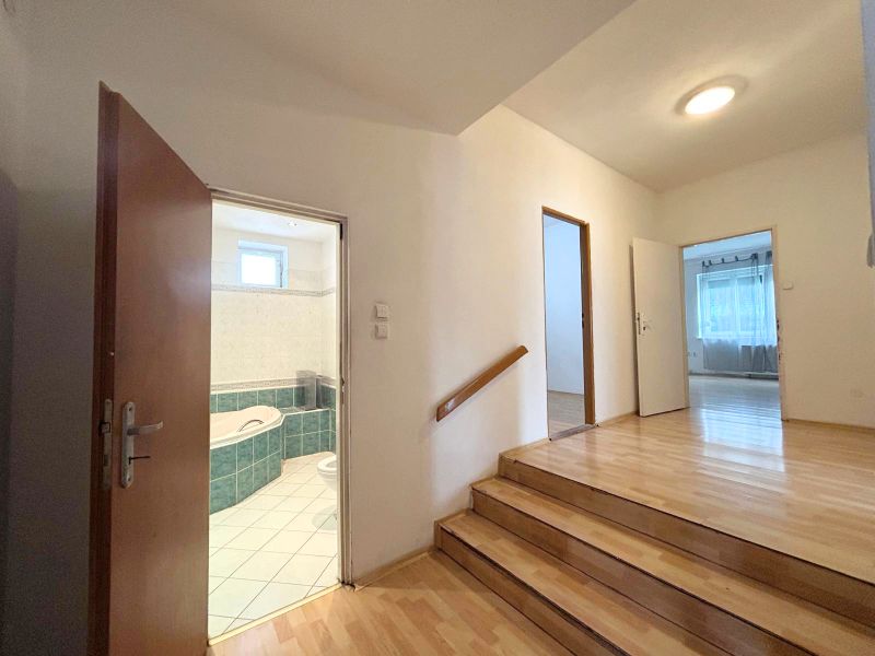 Eine Treppe mit einem Boden in Holzoptik, die in einem Einfamilienhaus ins Badezimmer führt.