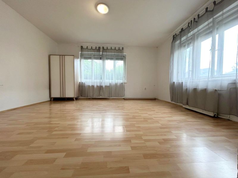 Innenraum eines Einfamilienhauses mit Holzboden und zwei Fenstern.