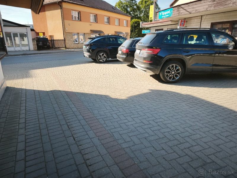 Parkplatz bei Geschäftsräumen in Turzovka mit Autos auf dem Pflaster.