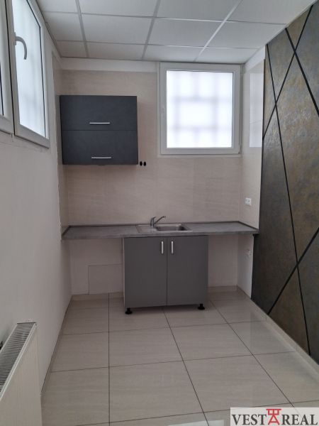 Büros mit Küchenzeile, Fliesen und grauem Schrank, geeignet für eine Arbeitsumgebung.
