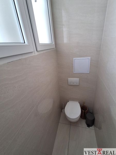 Badezimmer im Büro mit geschlossenem WC und einfachen Fliesen.