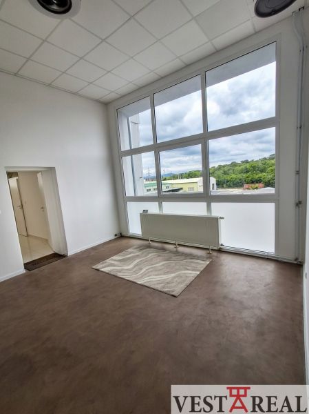 Ein Büro mit einem großen Fenster, einem Boden mit Holzdekor und Fußbodenheizung.
