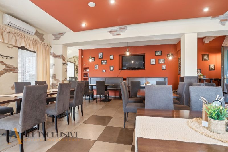 Restaurantinnenraum mit orangefarbener Wand, Sitzgelegenheiten und Dekorationen in gastronomischen Räumen.