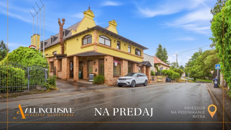Straße mit einem Gebäude für Gastronomieräume zum Verkauf in Nitra, gesäumt von Grünflächen und einem Parkplatz.