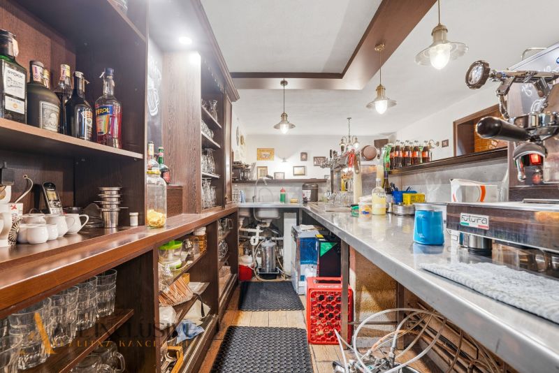 Innenraum eines Gastronomiebereichs mit Bar und Getränken auf den Regalen, Boden mit Holzdekor.
